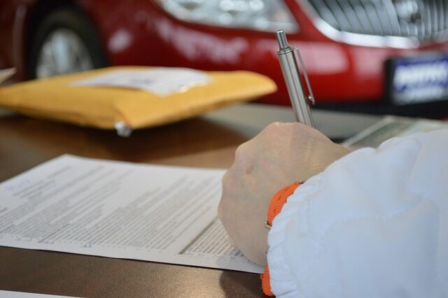 A hand holding a pen signing on a paper