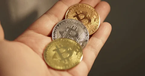 Hand holding three crypto coins
