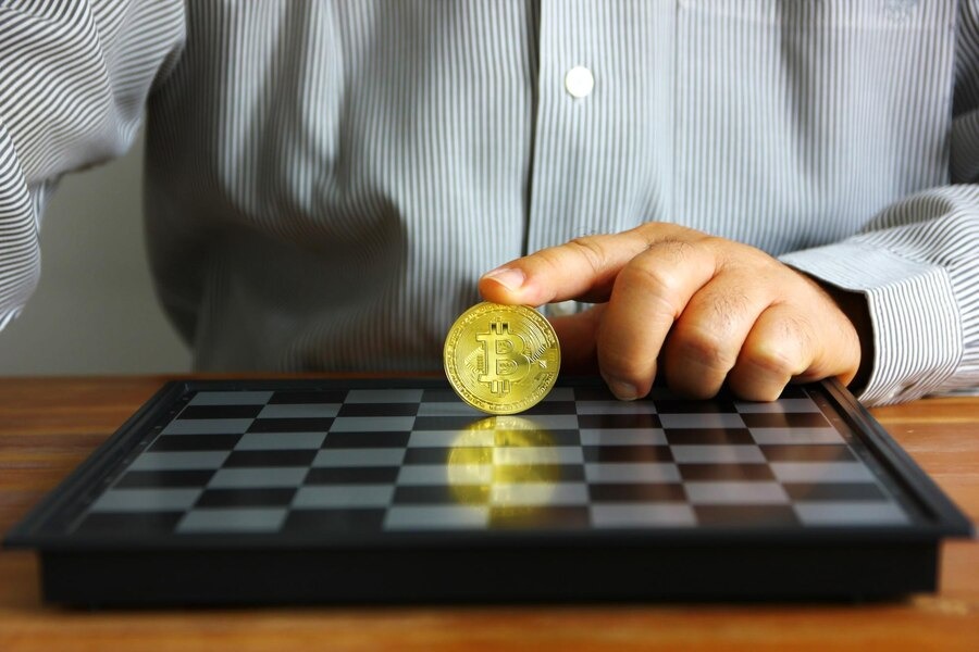 Index finger put on Bitcoin on a chessboard.