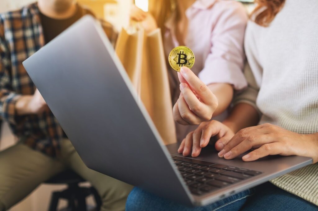 Group of young people using laptop and bitcoin for shopping online together.
