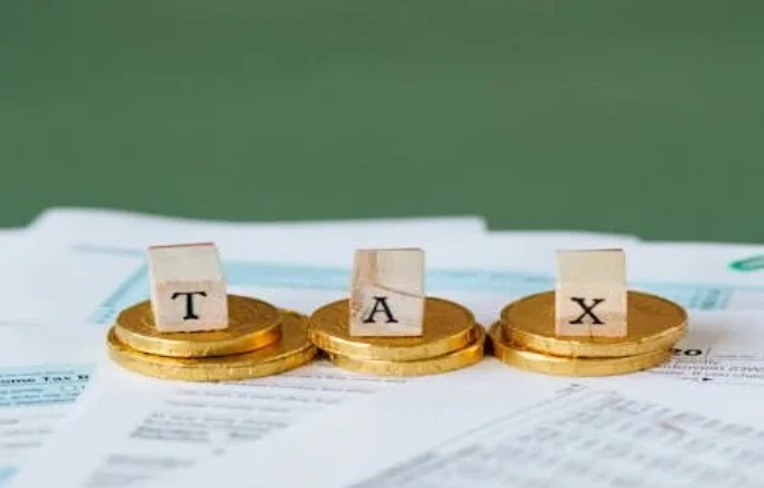 Gold coins on top of documents with inscriptions of TAX