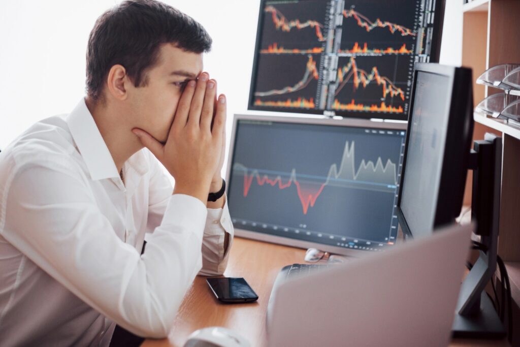 Stockbroker in a shirt working in a monitoring room with display screens.