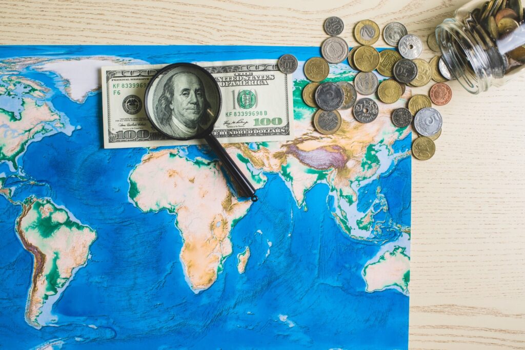 Map of the world with money and a magnifying glass