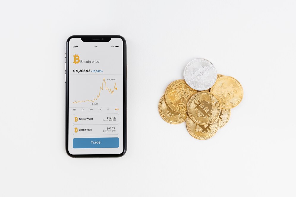 Pile of crypto coins with phone showing Bitcoin trading chart