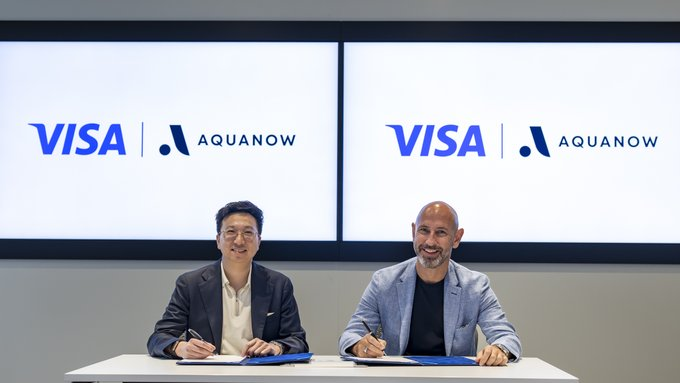 Visa and Aquanow representatives signing a paper